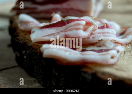 Deliziosa tutta artigianale affumicata pancetta lastra su un blocco di taglio Foto Stock