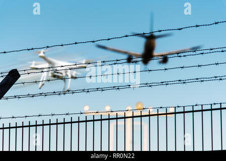 Quadcopter drone in volo vicino al velivolo avvicinando pista di aeroporto Foto Stock