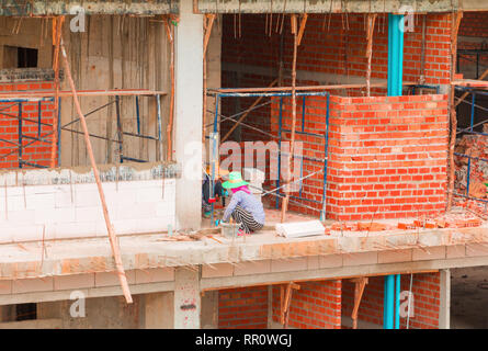 Muratore lavoratore di sesso femminile che di lavoro installazione industriale di mattoni della parete nel sito in costruzione Foto Stock