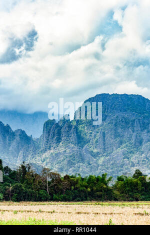 Splendida vista di alcune montagne calcaree illuminata da alcuni raggi di sole che filtrano attraverso alcune nuvole. Vang Vieng, Laos. Foto Stock