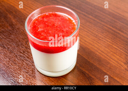 Fragola panna cotta dessert in un vetro isolato su una tavola di legno ricetta idea Foto Stock