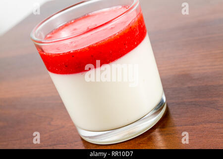 Fragola panna cotta dessert in un vetro isolato su una tavola di legno ricetta idea Foto Stock