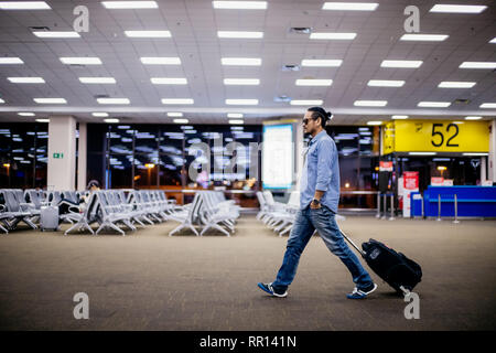 Uomo asiatico traveler con le valigie a piedi ed il trasporto di un aeroporto Foto Stock