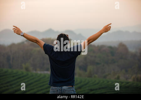 La libertà degli uomini di viaggiatori in piedi con le braccia sollevate e godendo di una splendida natura e rasserenanti giovani al tramonto,Relax Tempo sul concetto di vacanza travel Foto Stock