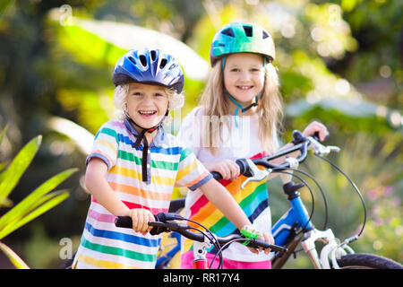 Ragazzi in bici nel Parco. Ai bambini di andare a scuola sicuro che indossa caschi da bicicletta. Piccolo Ragazzo e ragazza in bicicletta sulla soleggiata giornata estiva. Active outdoor sano sp Foto Stock