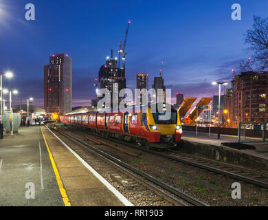 Un Sud Occidentale classe ferroviaria 707 chiamando alla Vauxhall, Londra al tramonto con la skyline di Londra dietro Foto Stock