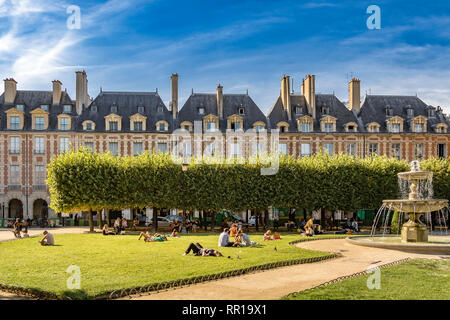 Persone seduti e prendere il sole sui prati di Place des Vosges , nel quartiere alla moda le Marais di Parigi, Francia Foto Stock