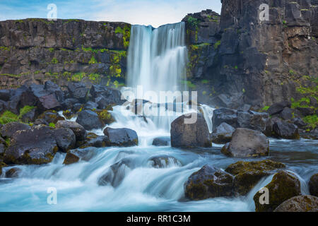 Cascata Oxararfoss che fluisce oltre le scogliere Almannagja, Pingvellir National Park, Sud dell'Islanda. Foto Stock