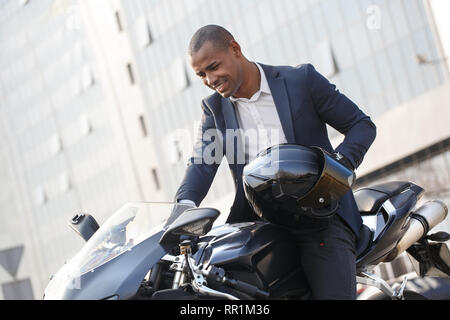 Giovane uomo seduto sul motociclo con casco motorino di avviamento eccitato Foto Stock