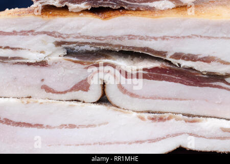 Pezzi di pancetta crudo come sfondo, close-up. Messa a fuoco selettiva Foto Stock