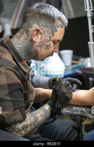 Brighton, Regno Unito. Il 23 febbraio, 2019. Tatuaggio artista lavora su un client in un dodicesimo annuale di Brighton Tattoo Convention presso il Centro di Brighton, Inghilterra. Credito: Jason Richardson/Alamy Live News Foto Stock