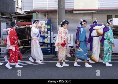 Tokyo, Giappone. 24 Febbraio, 2019. I partecipanti vestiti nelle donne il kimono e indossando il trucco, correre di casa in casa per scacciare gli spiriti maligni durante la Ikazuchi no Daihannya festival. Volontari Festival di portare i contenitori 6 dal tempio Shinzoin intorno al quartiere di scacciare gli spiriti malvagi.Â Le origini di questo evento annuale sono contestati, ma la leggenda dice il sacerdote del tempio Shinzoin hanno visitato casa per casa per impedire la diffusione del colera durante la tarda epoca Edo. Un'altra leggenda di un uomo che ha vissuto nel quartiere vestito di donna kimono per spaventare i cattivi spiriti per h Foto Stock