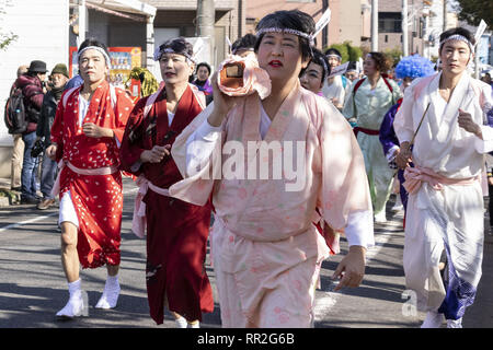 Tokyo, Giappone. 24 Febbraio, 2019. I partecipanti vestiti nelle donne il kimono e indossando il trucco, correre di casa in casa per scacciare gli spiriti maligni durante la Ikazuchi no Daihannya festival. Volontari Festival di portare i contenitori 6 dal tempio Shinzoin intorno al quartiere di scacciare gli spiriti malvagi.Â Le origini di questo evento annuale sono contestati, ma la leggenda dice il sacerdote del tempio Shinzoin hanno visitato casa per casa per impedire la diffusione del colera durante la tarda epoca Edo. Un'altra leggenda di un uomo che ha vissuto nel quartiere vestito di donna kimono per spaventare i cattivi spiriti per h Foto Stock