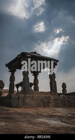 Piccolo tempio di pietra con drammatica mystic cielo nuvoloso hampi india karnakata Foto Stock