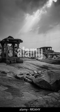 Piccolo tempio di pietra con drammatica mystic sky in hampi india karnakata in bianco e nero Foto Stock