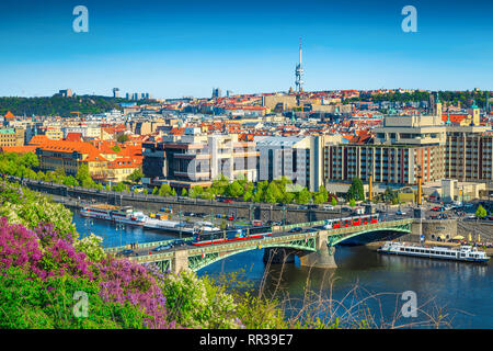 Splendido centro turistico e meta di viaggio. Il fiume Moldava e ponte rosso con i tram. Centro citta' con colorati fiori di primavera nel parco pubblico, Praga, C Foto Stock