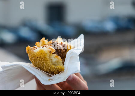 Un arancino, tipico siciliano di cibo di strada fatta di riso allo zafferano e la carne in un panate sfera Foto Stock