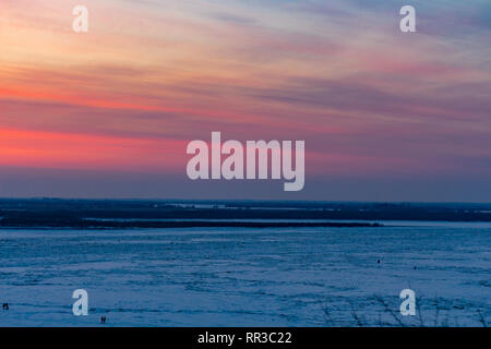 Bel tramonto oltre il fiume Amur a Khabarovsk. L'inverno. Frozen River. La gente a piedi sul ghiaccio. Foto Stock
