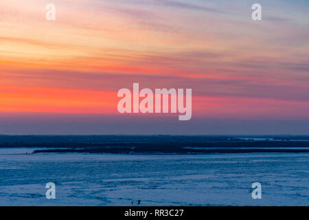 Bel tramonto oltre il fiume Amur a Khabarovsk. L'inverno. Frozen River. La gente a piedi sul ghiaccio. Foto Stock