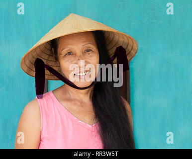 Primo piano volto ritratto di donna vietnamita indossando cappello conico Foto Stock