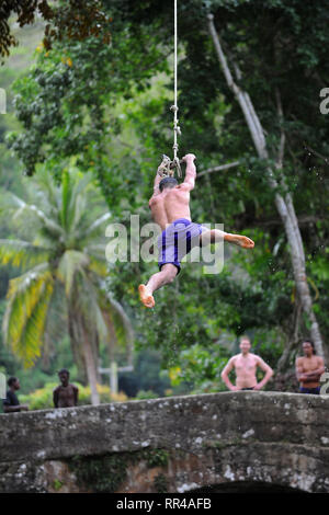Un uomo oscilla su una corda in spagnolo vecchio ponte che collega San Ann e Santa Maria delle parrocchie oltre il Fiume Bianco, Giamaica. Foto Stock