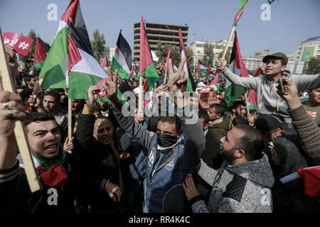 La striscia di Gaza, Territori palestinesi. 24 Febbraio, 2019. La gente in attesa bandiere palestinese prendere parte a una protesta esigente il presidente palestinese Mahmoud Abbas al passo verso il basso. Credito: Mohammed Talatene/dpa/Alamy Live News Foto Stock