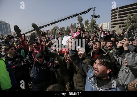 La striscia di Gaza, Territori palestinesi. 24 Febbraio, 2019. Persone tengono le scarpe e le indicazioni che prendono parte a una protesta esigente il presidente palestinese Mahmoud Abbas al passo verso il basso. Credito: Mohammed Talatene/dpa/Alamy Live News Foto Stock