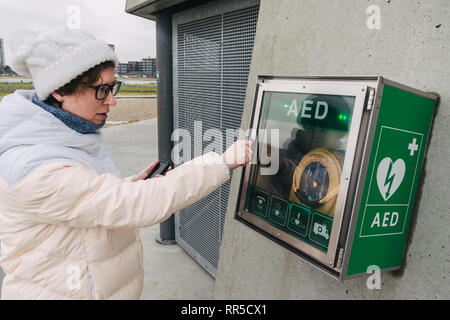 Medicina rianimazione cardiopolmonare chiamata di emergenza. La donna caucasica utilizza telefono chiamando 911 aiuto. il riquadro del dispositivo aed defibrillatore automatico malattia Foto Stock