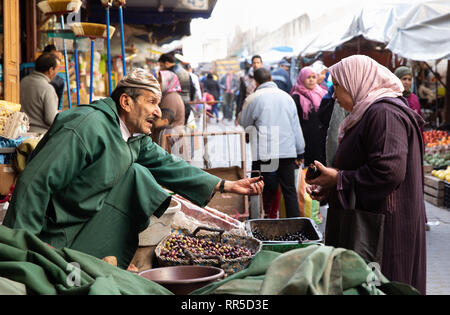 Olive il fornitore e il cliente nel souq di Fes Medina Foto Stock