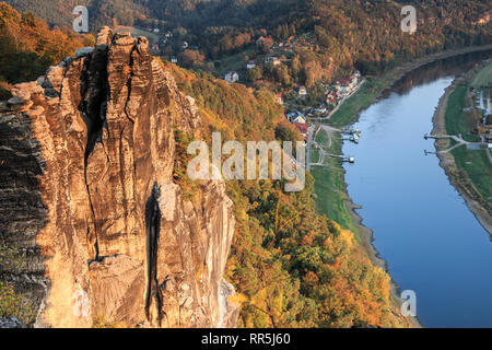 Formazione di rocce e alberi con sole serale in autunno. Sullo sfondo di foreste e case, nella valle del fiume Elba dalla Svizzera sassone Foto Stock