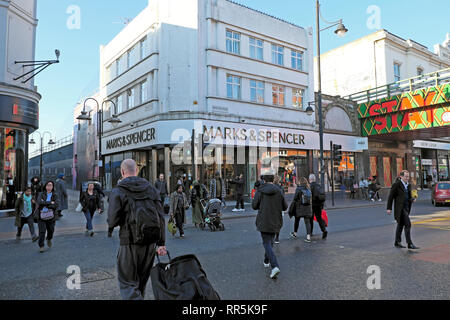 Shoppers pedoni attraversare la strada al semaforo di Marks & Spencer store su Brixton Road di Brixton, Sud Londra UK KATHY DEWITT Foto Stock