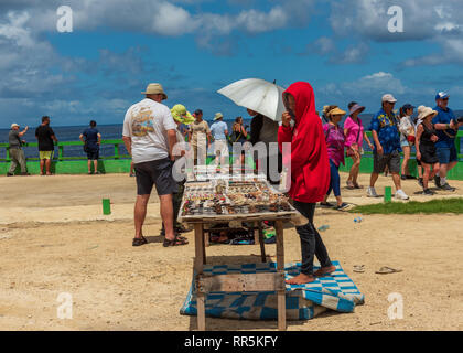 Costa, Tonga--marzo 10, 2018. Un mercante Tonganese ha predisposto un tavolo con negozio di souvenir vicino a un punto di vedetta frequentemente visitato da turisti. Foto Stock