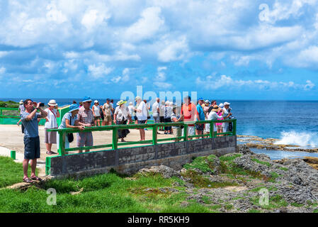 Costa, Tonga -- Marzo 10, 2019. Turisti si riuniscono su una piattaforma in riva al mare a guardare l'acqua sparare attraverso soffiature. Foto Stock