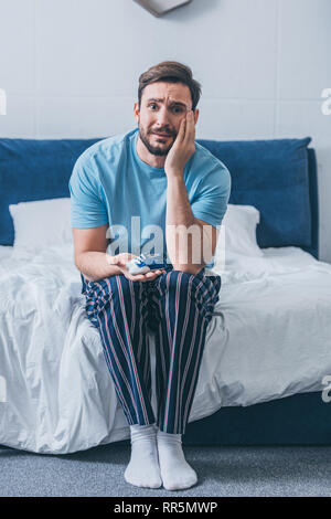 Il lutto padre seduto sul letto, guardando la fotocamera e azienda scarpe per bambini a casa Foto Stock