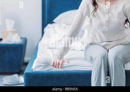 Vista ritagliata della donna in pigiama seduto sul letto con spazio di copia Foto Stock