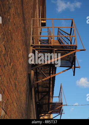 Edificio di mattoni con fire escape contro il cielo blu Foto Stock