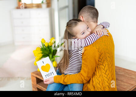 Adorabile ragazza dando la sua mamma, giovane malato di cancro, in casa Io amo mamma biglietto di auguri. Festa di famiglia concetto. Felice Festa della Mamma o Birthda Foto Stock