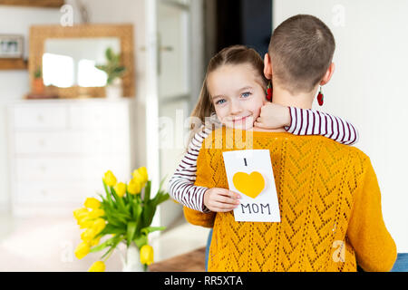 Felice Festa della mamma Festa di compleanno o di sfondo. Adorabile ragazza dando la sua mamma, giovane malato di cancro, in casa Io amo mamma biglietto di auguri. Famiglia celebra Foto Stock