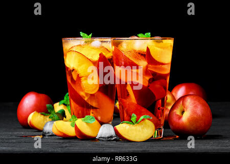 Peach ice tea in un bicchiere con la menta su tavoli in legno nero(fuoco selettivo). Foto Stock