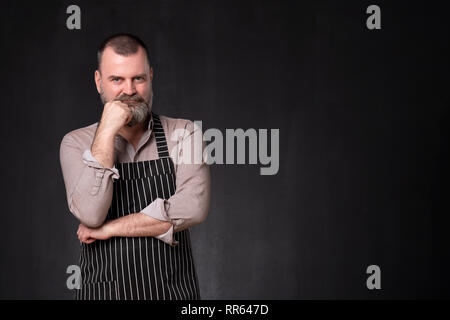 Coppia uomo bello con la barba che indossa il grembiule con un espressione di fiducia Foto Stock