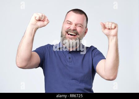 Emotiva di successo uomo maturo urlando sì e sollevando rinserrata pugni in aria Foto Stock