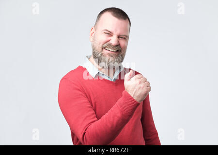 Emotiva di successo uomo maturo urlando sì e sollevando rinserrata pugni in aria Foto Stock