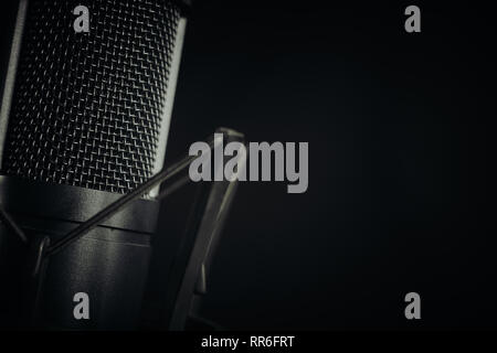 Abstract close up di un studio microfono a sinistra del telaio contro uno sfondo scuro, aspetto orizzontale. Focus sulla rete di sommità. Foto Stock