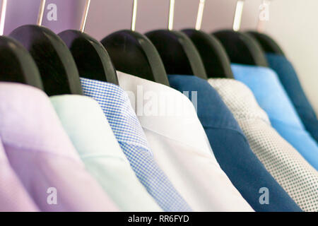 Molti uomini camicie di colori diversi sulle staffe. Messa a fuoco selettiva Foto Stock