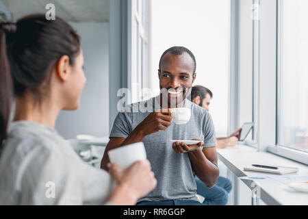 Ritratto di dipendenti multiculturale vestito in abbigliamento casual, ridere mentre godendo la pausa caffè durante il processo di lavoro in un ufficio moderno interno, beh Foto Stock
