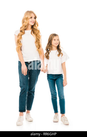 Madre sorridente e adorabile figlia in bianco t-shirt e jeans blu holding hands isolato su bianco Foto Stock