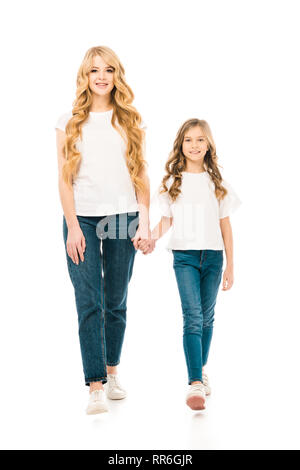 Madre bella e adorabile figlia in bianco t-shirt e jeans blu holding hands isolato su bianco Foto Stock