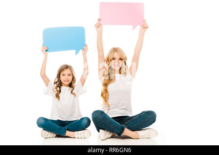Bambino adorabile e bella madre seduto sul pavimento con le gambe incrociate e tenendo i fumetti in alzare le mani su sfondo bianco Foto Stock