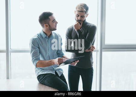 Due imprenditori sorridente parlando di investimenti ammissibili, manager presentando una relazione finanziaria che mostra un buon lavoro risulta soddisfatto collega, punto Foto Stock