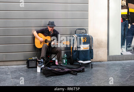 Suonatore ambulante britannico di cantare e suonare la chitarra su una strada commerciale di Siviglia, Spagna Foto Stock